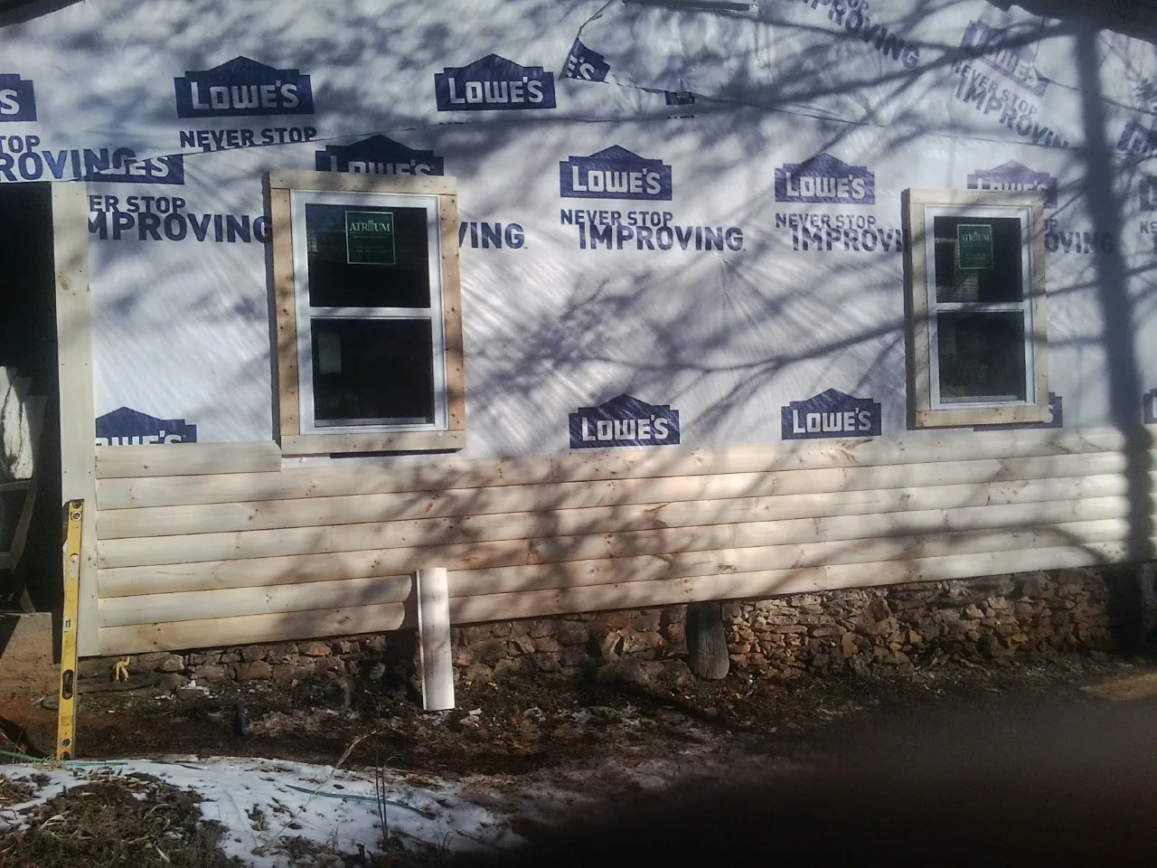House wrap and new log siding going up on an exterior wall in Lake Powell