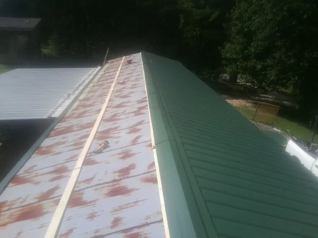 Old rusted panels beside newly installed green metal roofing — Wind Damage Roof Repair by Roofing Brothers in Lake Powell