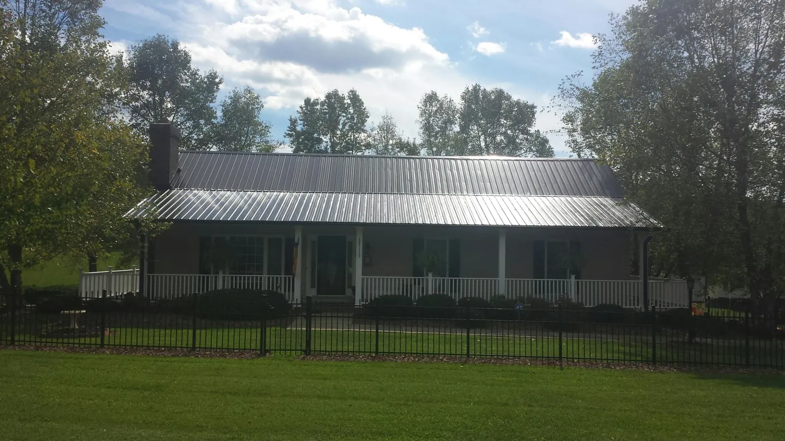 Gray metal roof on a brick ranch with a full width front porch — Gutter Guard Installation work by our crew in Lake Powell
