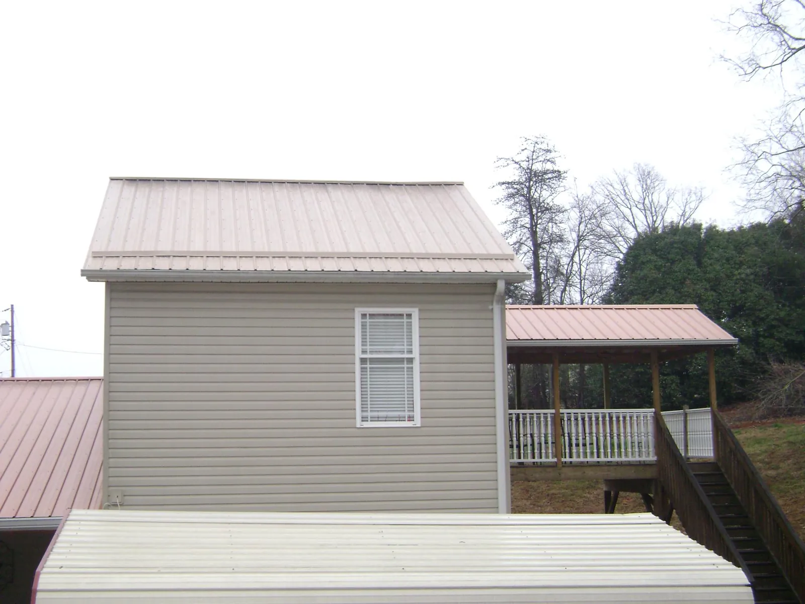 Tan metal roofs on a two story addition and attached porch, from a Roof Replacement job in Lake Powell