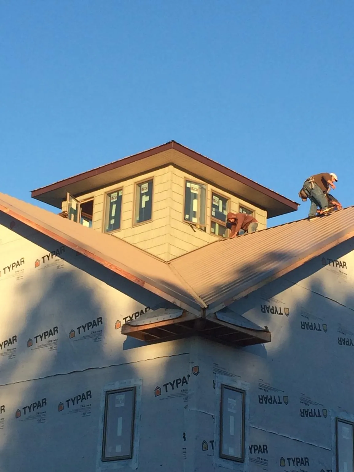 Roofers working around a rooftop cupola on a new metal roof at sunset — Roof Waterproofing in Lake Powell by Roofing Brothers